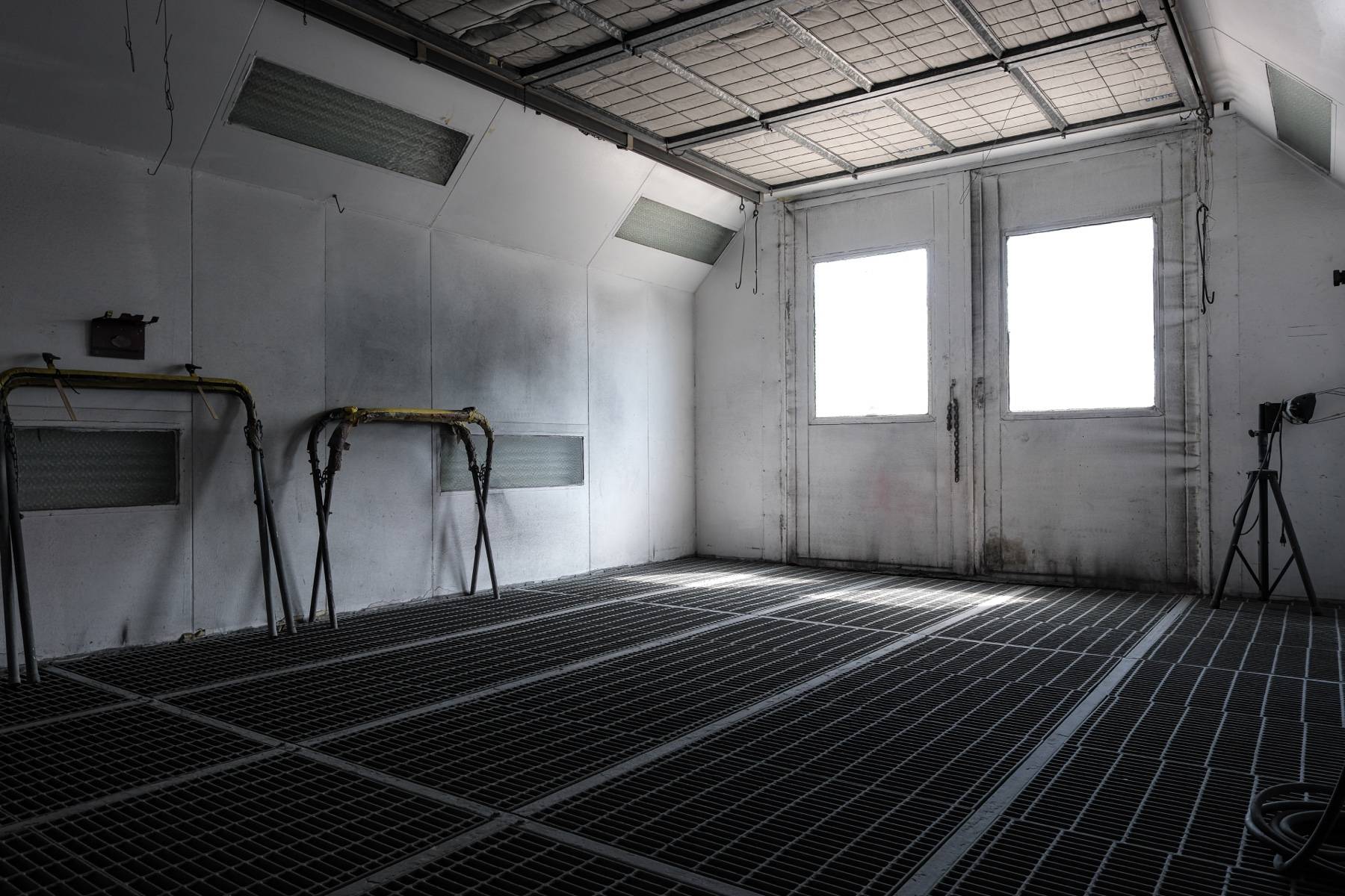 The empty spray booth: grated floor, filtered ceiling, and panel stands along the wall.