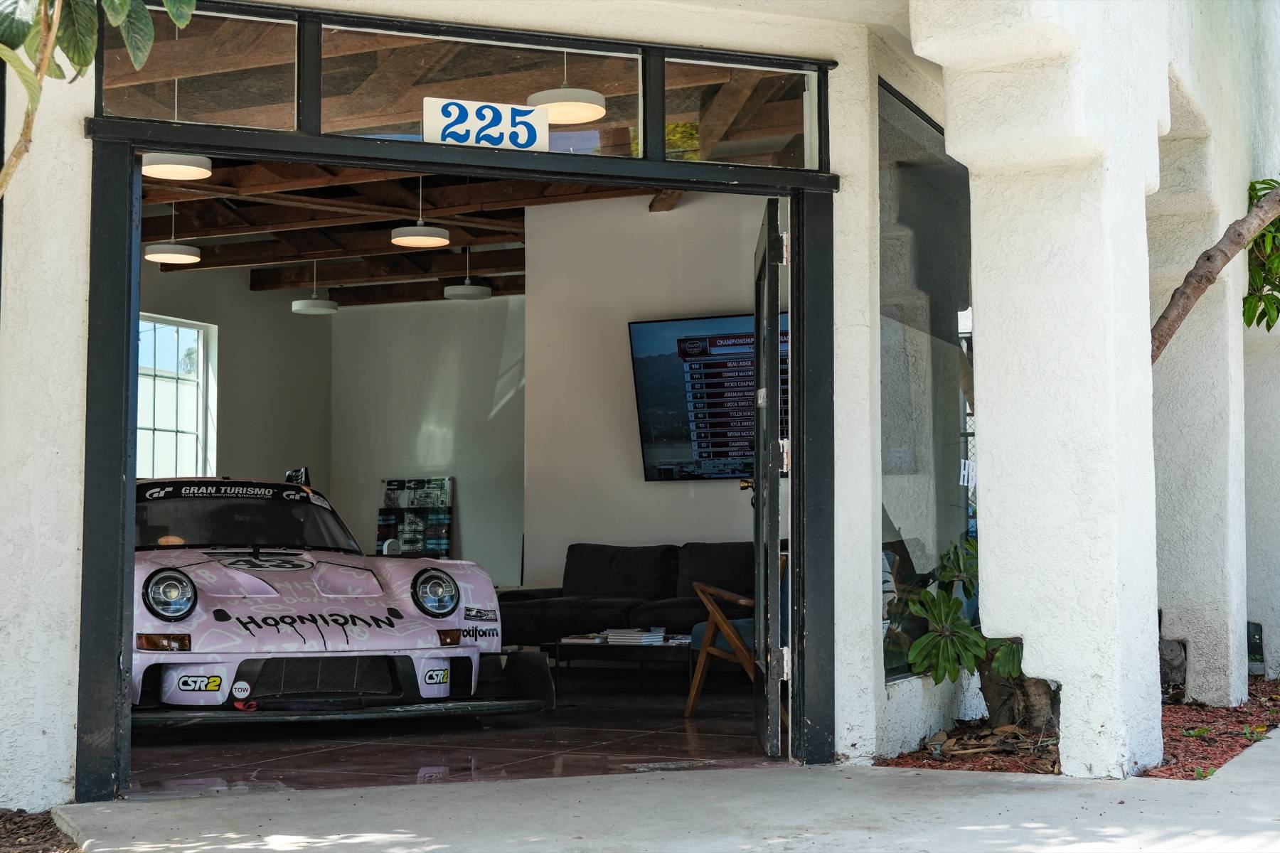 The open roll-up door at 225 5th St, the lounge and the Hoonigan 911 visible inside.