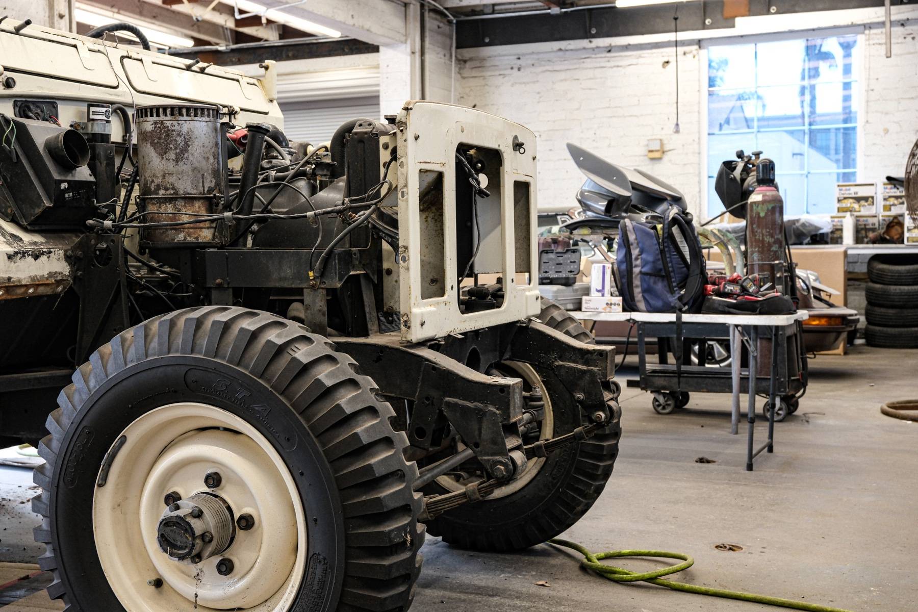 The front of a vintage Land Rover stripped down to its chassis and running gear in the body shop.