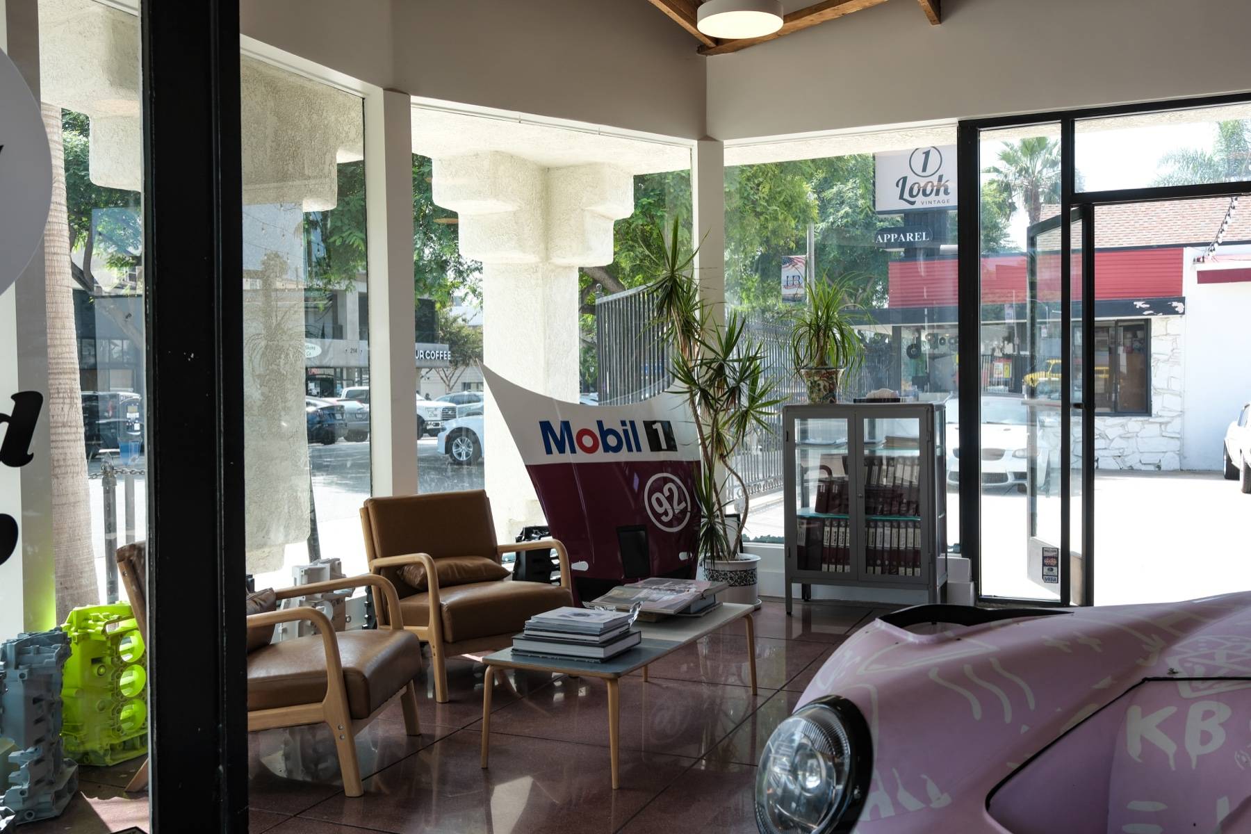 Leather armchairs and a coffee table in the glass-walled corner, a Mobil 1 race-car panel on display.